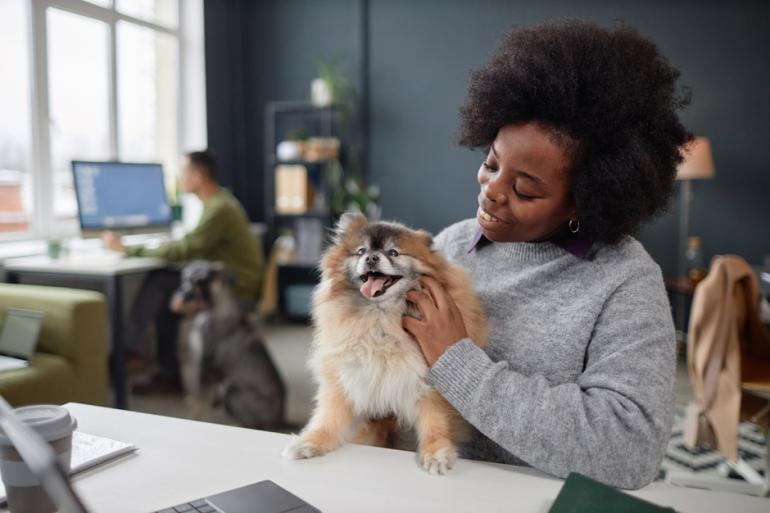 Mujer consintiendo a su mascota en la oficina